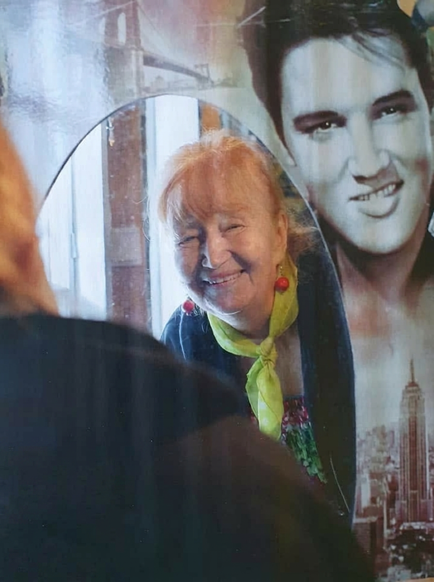 Marjatta peilin vieressä Elvis-julisteen äärellä
